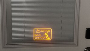 Puerta con un letrero de precaución que indica tener cuidado al bajar.
