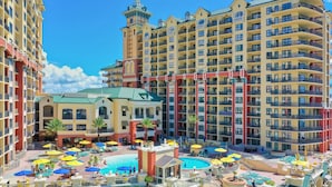 A multi-story hotel with a central pool area, multiple balconies, and a distinctive tower. - Emerald Grande W729 (Destin)