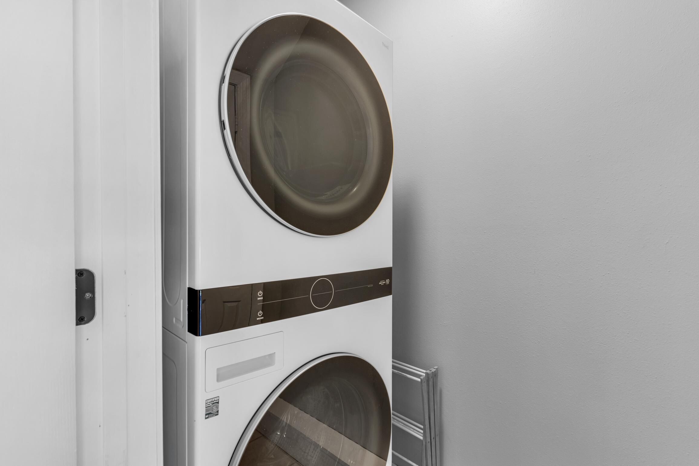 Un appareil combiné lave-linge et sèche-linge, de type « superposé », dans une pièce moderne au style minimaliste.