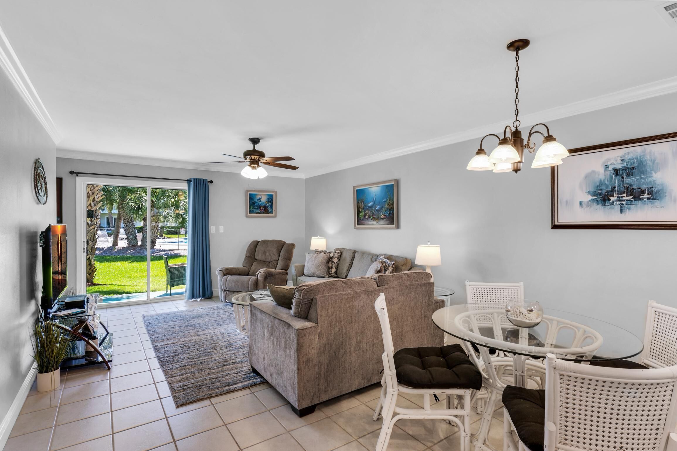 A spacious living room with a sofa, chairs, a dining table, and a ceiling fan.