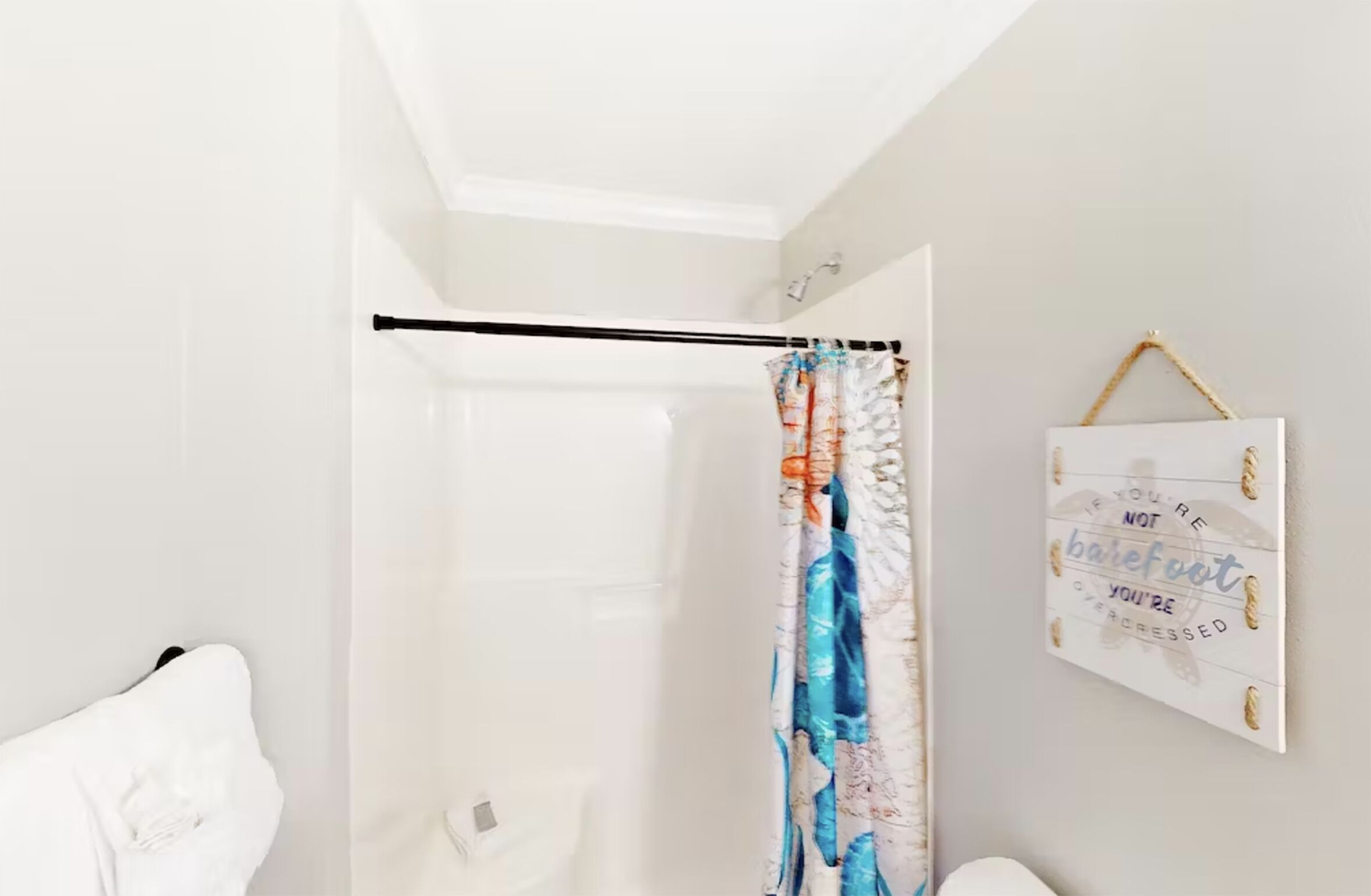 A bathroom with a shower curtain, a towel rack, and a motivational quote on the wall.