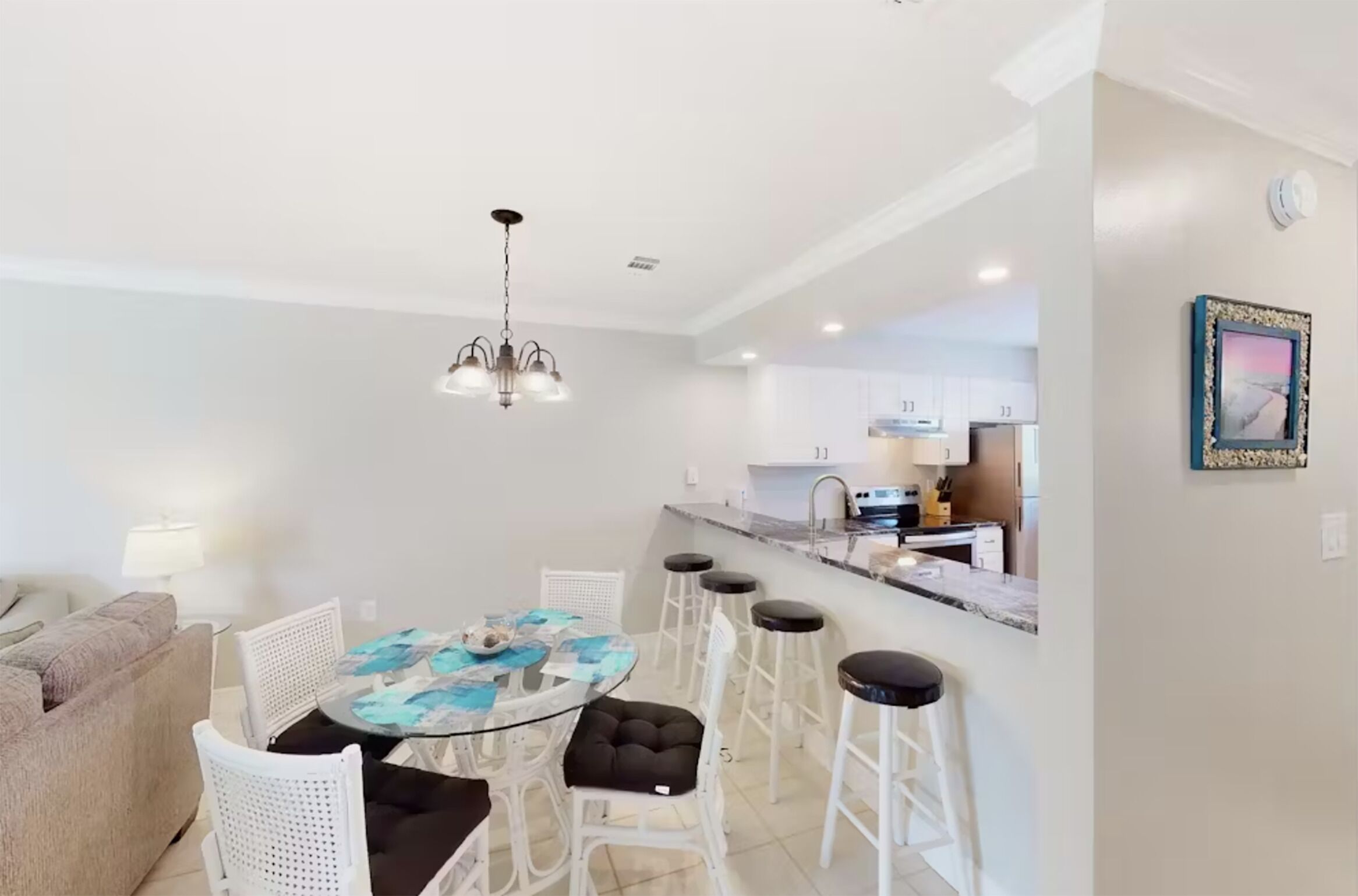 Une cuisine moderne avec des armoires blanches, un comptoir en marbre et un luminaire suspendu.