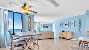 A spacious living area with a dining table, sofa, and a view of the ocean.