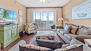 A living room with a sofa, armchairs, a coffee table, a TV, and a ceiling fan. - Ariel Dunes II 1007- Son-sent Blessings (Miramar Beach)