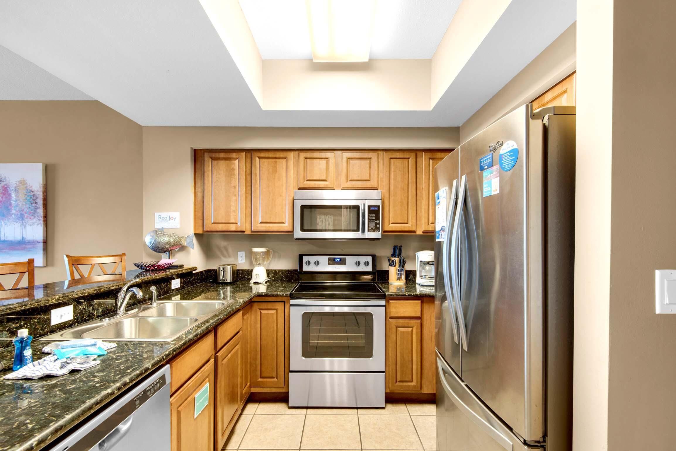 A modern kitchen with wooden cabinets, stainless steel appliances, and a granite countertop.