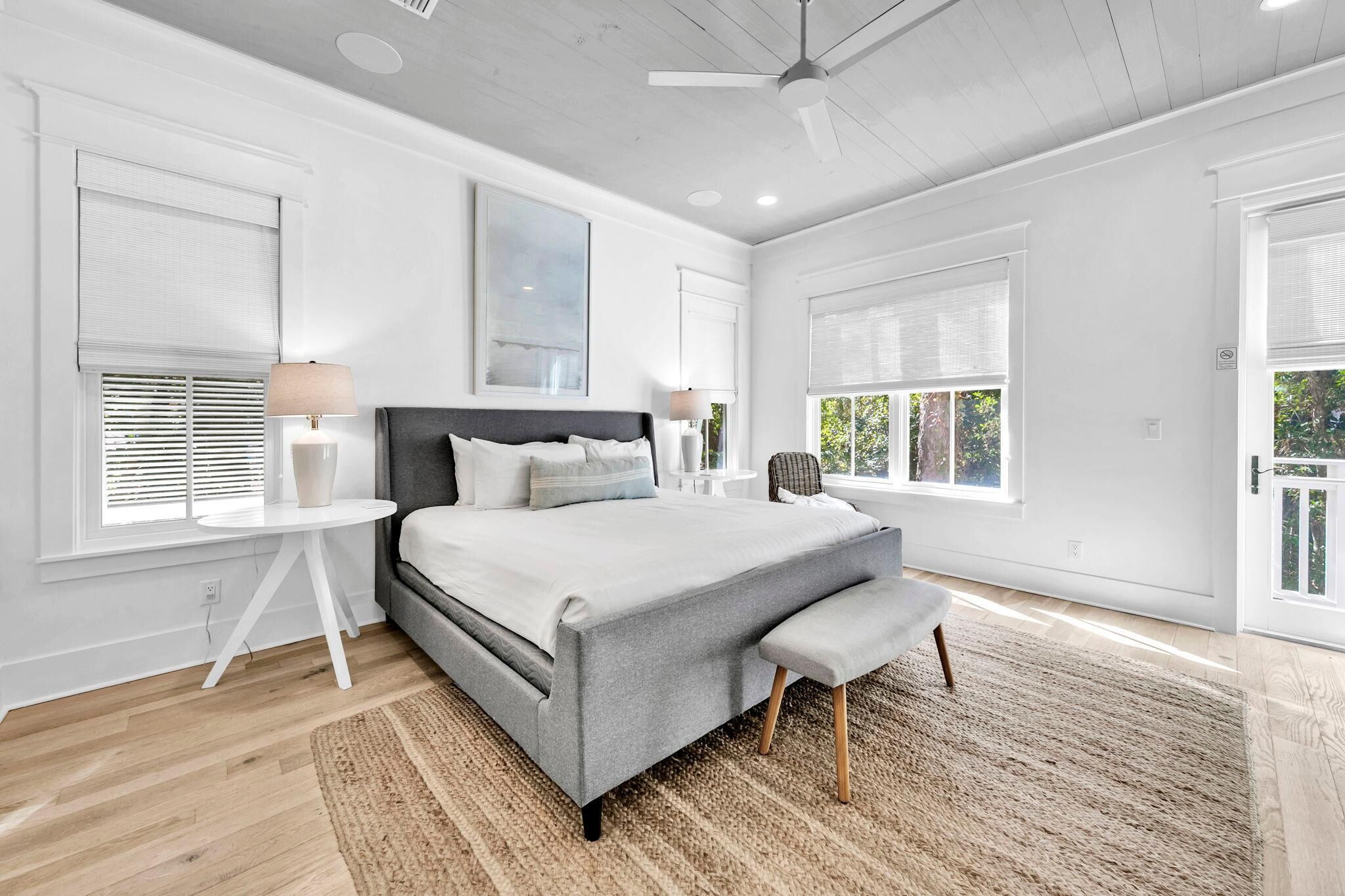 Una camera da letto moderna con un letto grande, una ventola a soffitto e ampie finestre.