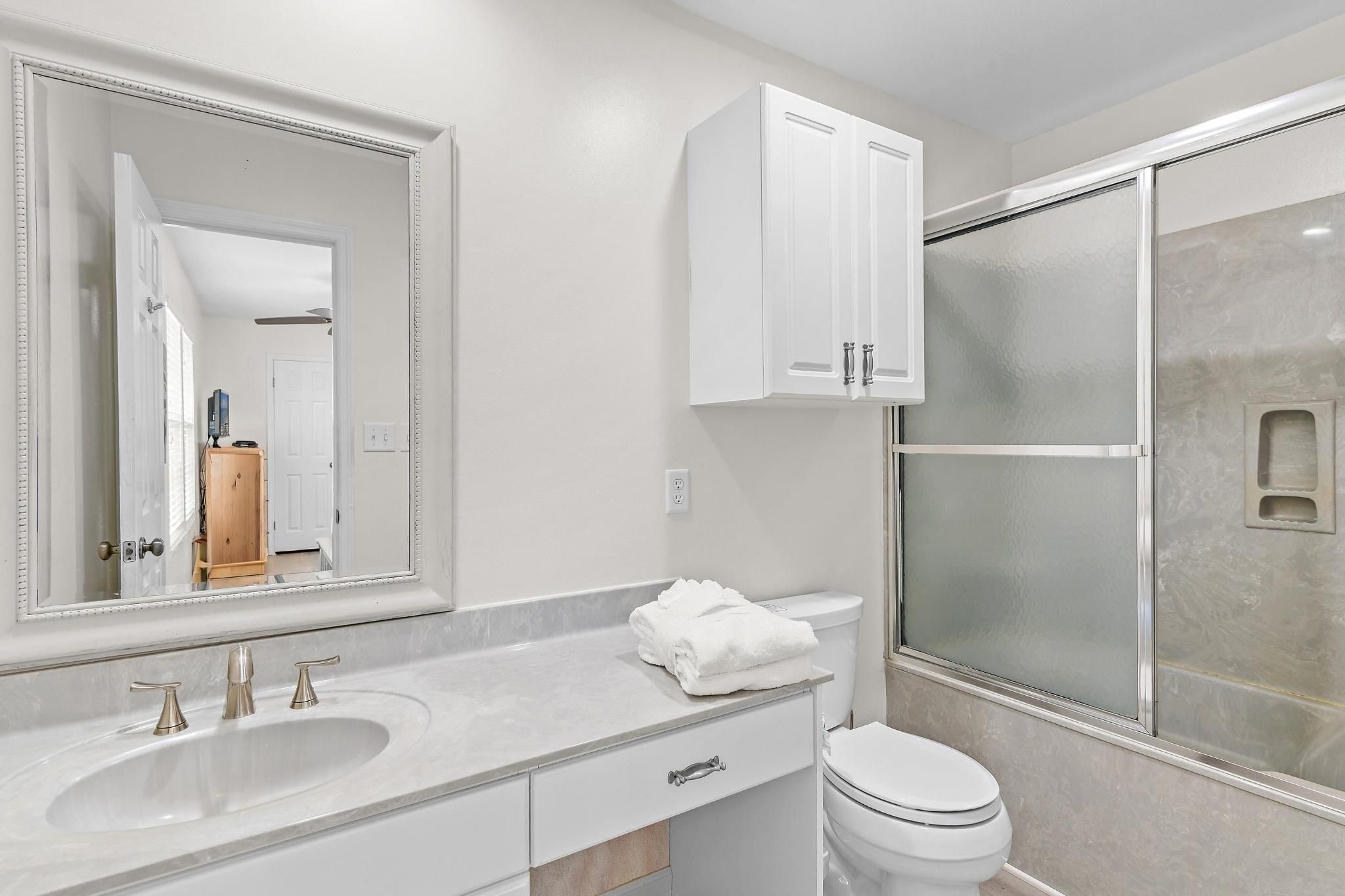 Une salle de bain moderne avec un grand miroir, un lavabo à deux robinets, des toilettes et un espace douche.