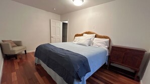 Une chambre à coucher avec un lit, une chaise, une armoire en bois et une porte.