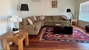 Un salon avec un canapé, une table basse, un tapis et une plante.