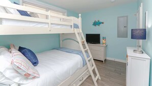 A bunk bed room with a TV, dresser, and a small cabinet. - Sojourn Ocean View Oasis Ocean & Bay Views (Virginia Beach)