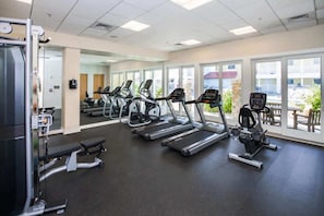 Un gimnasio con cintas de correr, elípticas y máquinas de pesas.
