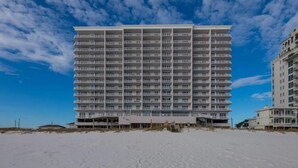 A high-rise hotel with multiple balconies, located on a beach with sandy ground. - Windemere 1204 (Pensacola)