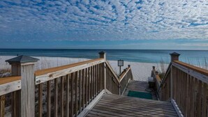 A wooden boardwalk leading to a beach with a clear view of the ocean and a partly cloudy sky. - Windemere 1204 (Pensacola)
