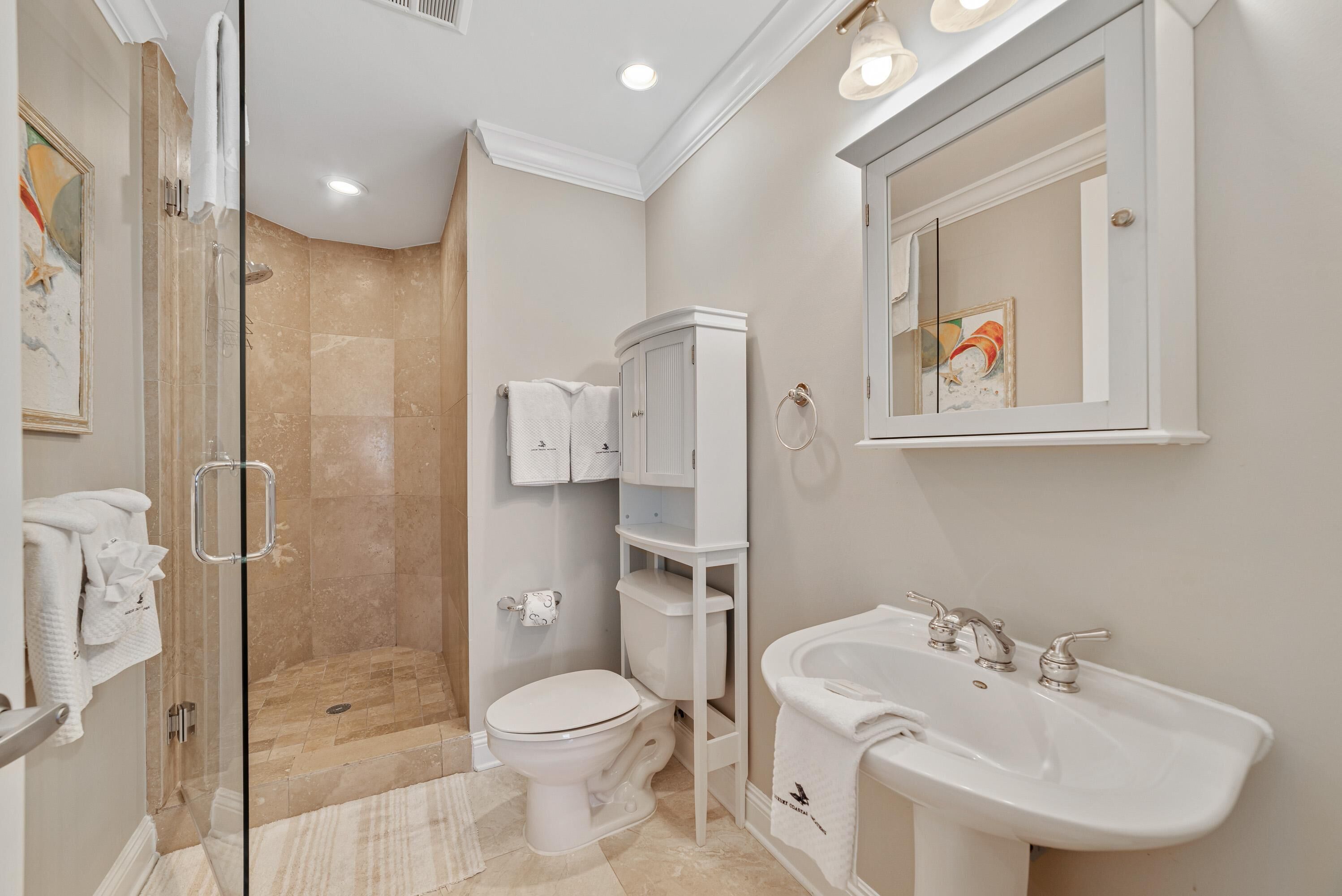 A bathroom with a glass-enclosed shower, a white toilet, a sink, and a cabinet.