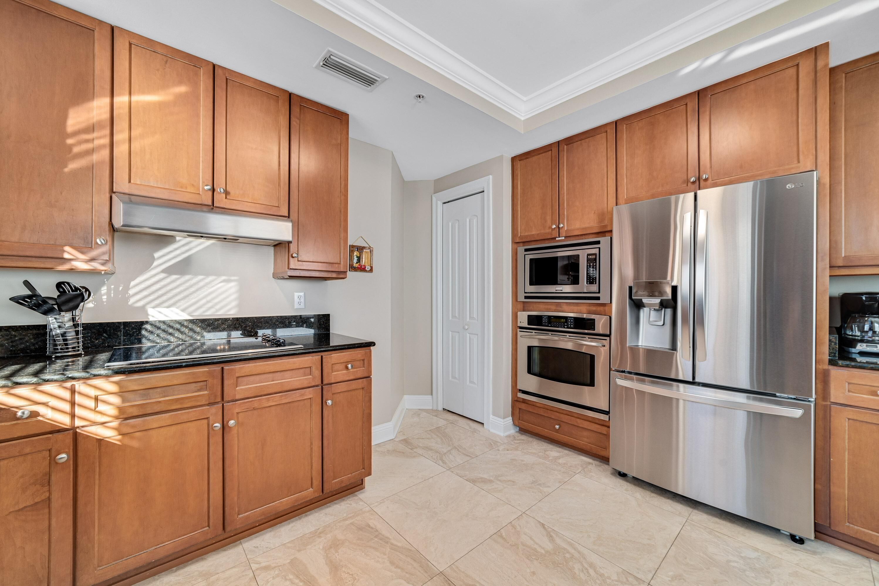 A modern kitchen with wooden cabinets, stainless steel appliances, and a black countertop.