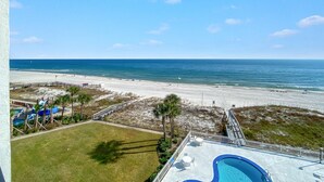A beach view from a hotel balcony with a pool, palm trees, and a sandy beach. - The Breakers 61 (Orange Beach)