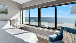 A hotel room with a large window offering a view of the beach and ocean. - The Breakers 61 (Orange Beach)
