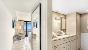 Una habitación de hotel moderna con un espejo grande, un sofá, una mesita y vistas al mar.