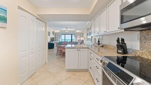 A modern kitchen with white cabinetry, a built-in microwave, and a granite countertop. - Shipwatch A402 (Pensacola)