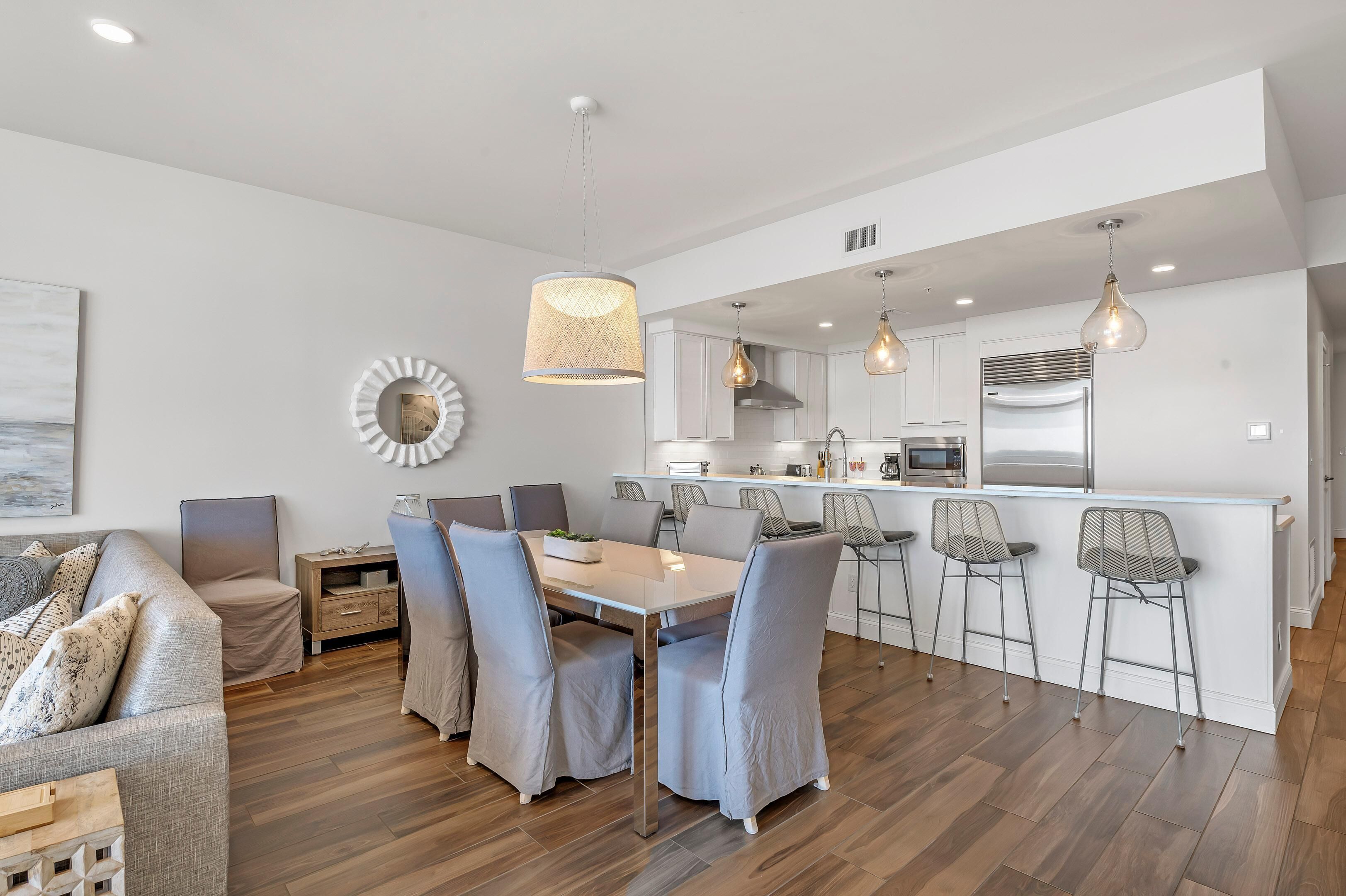 Een moderne keuken met een centraal eiland, barkrukken en hanglampen.