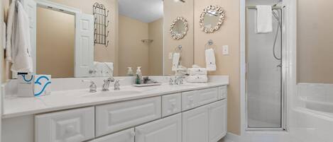 A modern bathroom with a large mirror, a shower, and a vanity with a sink and towel rack.