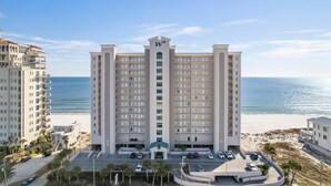 Um hotel moderno com vários sacadas, entrada central e vista para a praia.