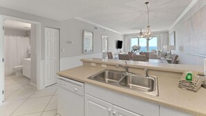 Cozinha moderna com uma ilha grande, pia de aço inoxidável e vista para a sala de estar.