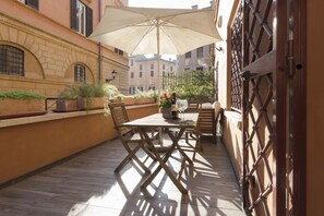 An outdoor patio with a wooden table and chairs, a large umbrella, and potted plants. - Domus Rinascimento (Piazza Navona) - Apartment with terrace (Roma)