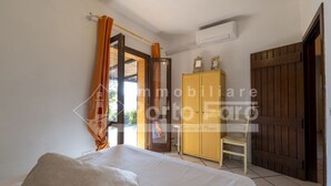 Une chambre à coucher comprenant un lit, une armoire et une porte donnant sur l’extérieur.