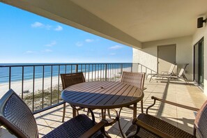 A balcony with a round table and chairs, overlooking a beach. - Shipwatch D601 (Pensacola)