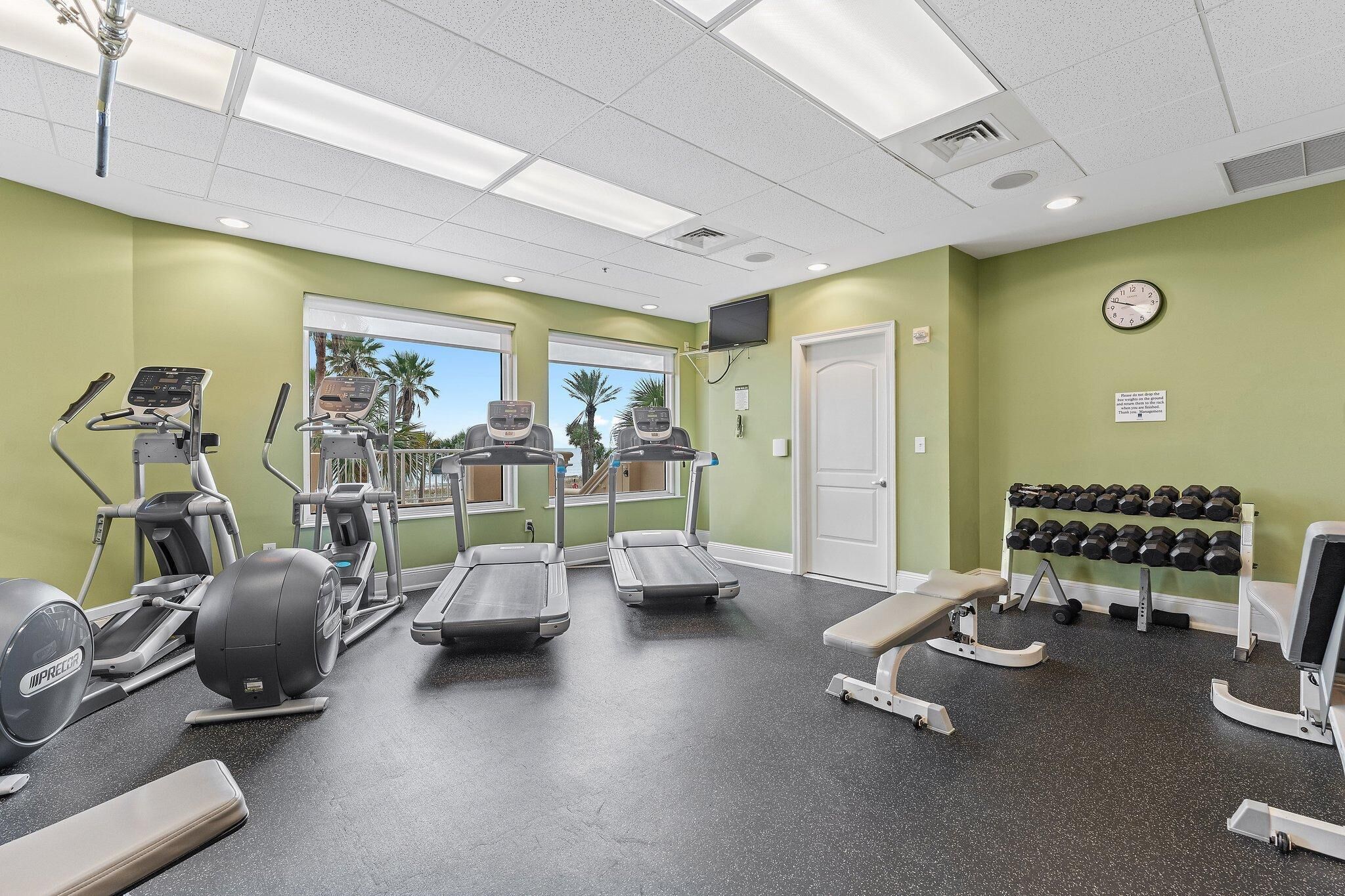 A gym with treadmills, elliptical machines, and a bench.