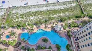 An aerial view of a resort with a large swimming pool, beach area, and a hotel building. - Indigo East 2104 Penthouse (Pensacola)