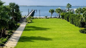A well-maintained grassy area with a pathway leading to a dock, surrounded by palm trees and a view of the water.
