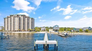 A waterfront hotel with a dock extending into the water, surrounded by buildings and greenery.