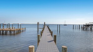 A wooden pier extending into calm water with a clear sky above.