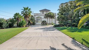 Asuinkiinteistö, jossa on ajotie, joka johtaa suurella autotallilla varustettuun taloon. Taloa ympäröivät hyvin hoidetut nurmikot ja palmuvalle.