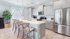 A modern kitchen with white cabinets, stainless steel appliances, and a central island with bar stools.