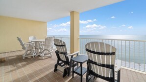 A balcony with a view of the ocean, white Adirondack chairs, and a small table. - Summer House 1203a (Orange Beach)