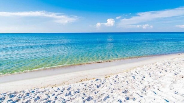 Een strand met helderblauw water en een zandstrand.