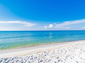 A beach with clear blue water and a sandy shore.