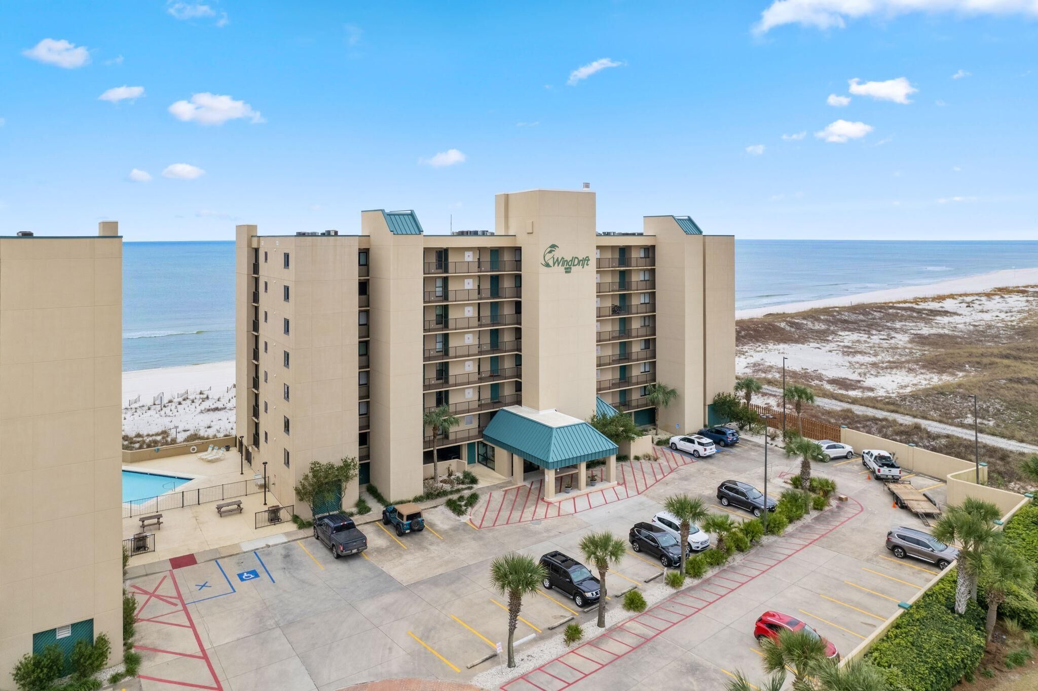 Ein Hotel mit Pool, Parkplatz und Blick auf den Strand.