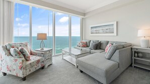 A living room with a view of the ocean, a sofa, a chair, a coffee table, and a lamp. - Mediterranean East 1101 (Pensacola)