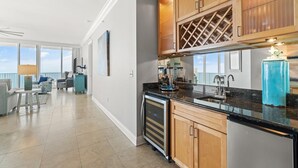 A modern kitchen with wooden cabinets, a stainless steel refrigerator, and a black countertop. - Mediterranean East 1101 (Pensacola)