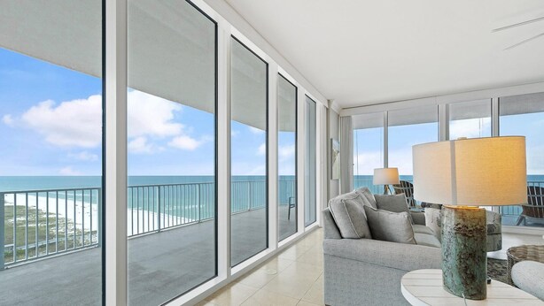 A spacious balcony with a view of the ocean, a grey sofa, and a table with a lamp. - Mediterranean East 1101 (Pensacola)