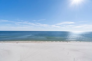 A wide, sandy beach with a clear blue sky and calm ocean.