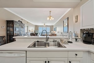A modern kitchen with a double sink, dishwasher, and coffee maker.