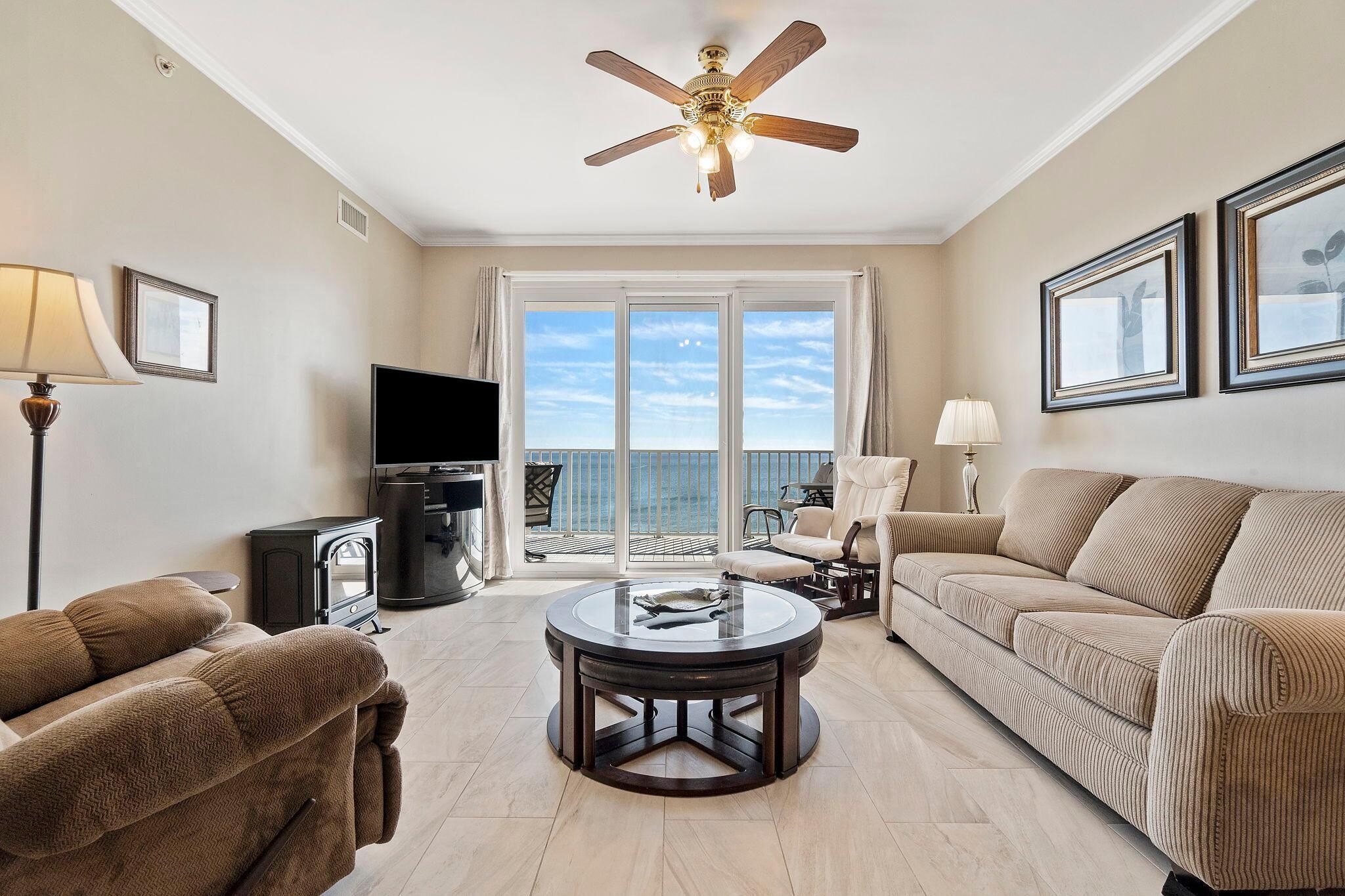 A living room with a sofa, a coffee table, a TV, and a ceiling fan.