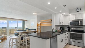 A modern kitchen with a central island, stainless steel appliances, and a view to the outside. - Perdido Sun 502 (Pensacola)