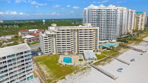 A high-rise hotel with multiple balconies, a swimming pool, and a beach area. - Perdido Sun 502 (Pensacola)
