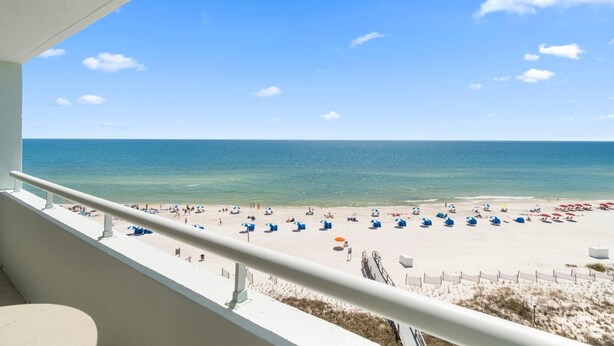 A balcony with a view of a beach with umbrellas and people. - Perdido Sun 706 (Pensacola)